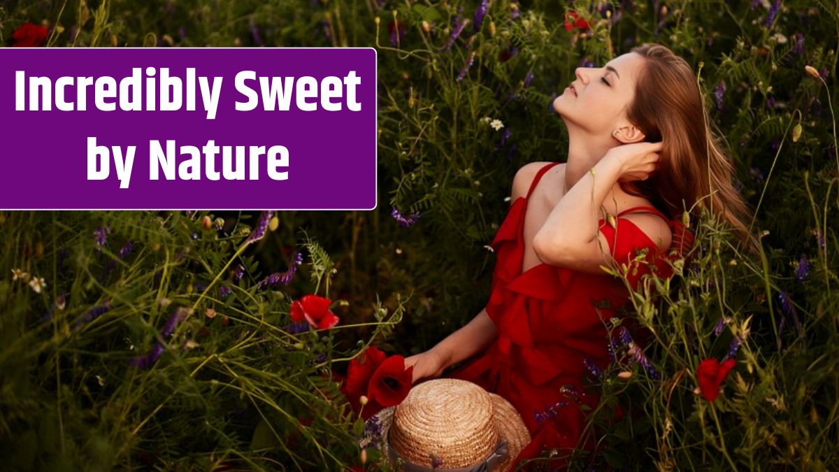 Stunning young woman in red dress sits on the green field with red poppies.