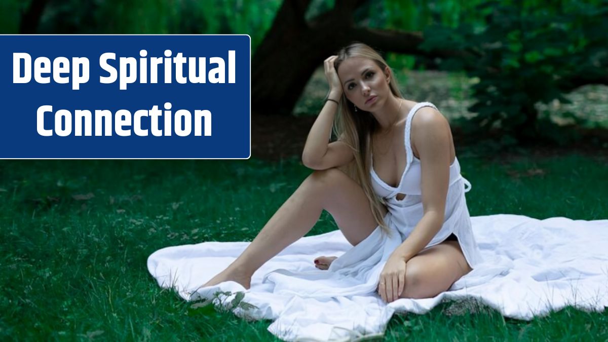 Portrait of smiling young woman sitting on grass against trees.