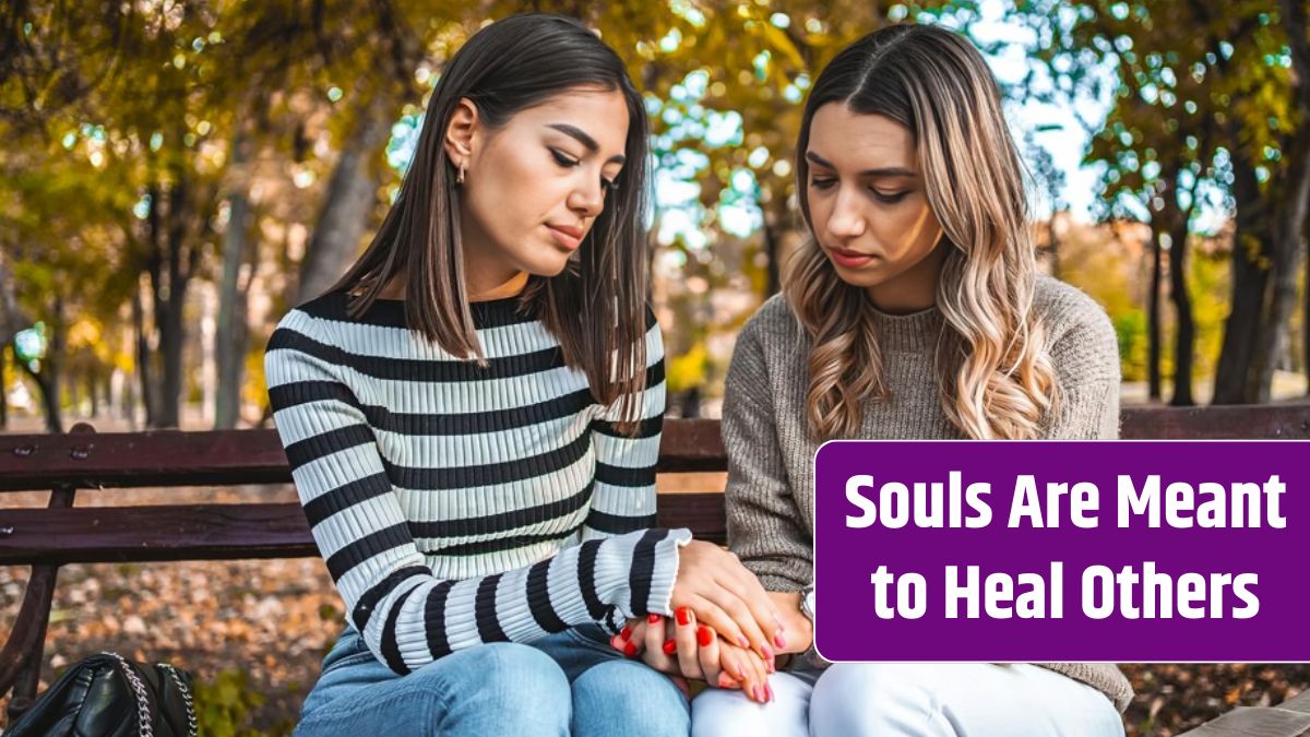 Two women sit on a bench holding hands in a sign of comfort and support.