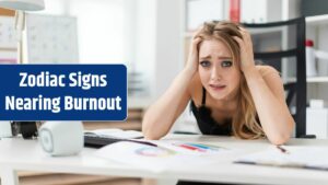 A young girl sits at a table in the office and holds her hands behind her head.